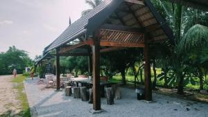Batu RakitSofea Homestay的凉亭,配有桌子、长椅和树木