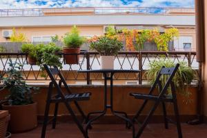 罗马Casa Francesca zona Gemelli的阳台上摆放着盆栽植物,配有一张桌子和两把椅子