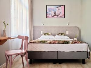 格丁尼亚HOLA GDYNIA的一间卧室配有一张床和一张粉红色的椅子