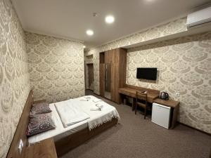 第比利斯5 Rooms near 300 Aragveli metro station的一间卧室配有一张床、一张书桌和一台电视