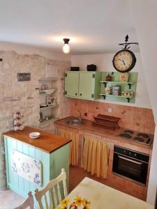 奥米什Vintage stone house ELDO in Podaspilje, Omiš的厨房配有绿色橱柜和墙上的时钟