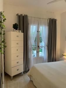 马贝拉Home Away From Home Marbella的一间卧室配有一张床、一个梳妆台和一扇窗户。
