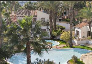 滨海罗克塔斯Casa con Encanto en Roquetas de Mar的享有棕榈树游泳池的顶部景致