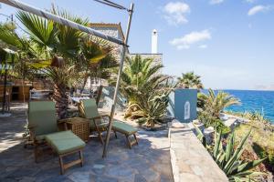 伊兹拉Lady of Hydra Villa, sea front view, private beach的一个带椅子的庭院和背景海洋