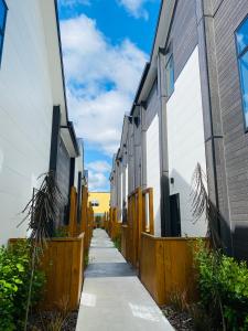 基督城Home sweet home Christchurch Centre的两栋建筑之间有一道人行道,有栅栏