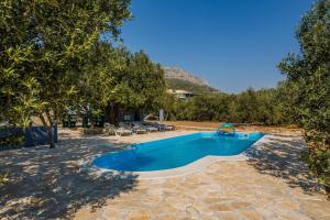 Kaštel SućuracLuxury private villa complex with pool and jacuzzi的一座位于庭院的游泳池,庭院里种着树木,房子里