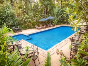 暹粒吴哥城堡住宿酒店的度假村旁的游泳池配有桌椅