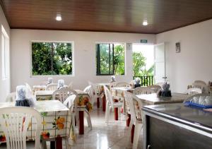 埃尔科莱希奥Finca Hotel Villa Gladys en Mesitas del Colegio的餐厅设有白色的椅子和桌子以及窗户。