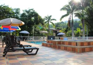 埃尔科莱希奥Finca Hotel Villa Gladys en Mesitas del Colegio的一个带椅子和遮阳伞的庭院和一个游泳池