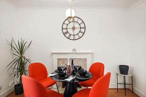 伦敦5 guests 3 beds 1 sofa bed Lewisham的一间用餐室,配有红色的椅子、一张桌子和闹钟