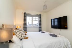斯特灵4 Bedroom Townhouse in Stirling的一间卧室设有一张带平面电视的床。