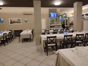 Mozzagrogna伊甸园公寓式酒店的一间用餐室,配有白色的桌椅和气球