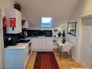 法尔茅斯Blue Hills Luxury Apartment, Coast Front, Parking的厨房配有白色橱柜和红色地毯的桌子