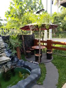 LocsinJLF Inn的花园设有池塘、桌子和遮阳伞