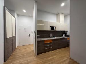 维也纳Vienna City Apartment 7的厨房铺有木地板,配有白色橱柜。