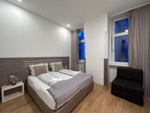 维也纳Vienna City Apartment 7的一间卧室配有一张床和一把椅子,还有两个窗户