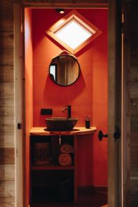 GesvesLes cabanes des Pierreux的浴室设有红色墙壁、水槽和镜子