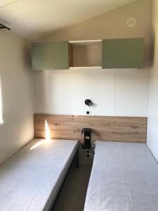 Bec-de-MortagneMobile-home Pin的一间设有两张床铺和绿色橱柜的房间