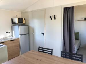 Bec-de-MortagneMobile-home Pin的一间带桌子和冰箱的小厨房