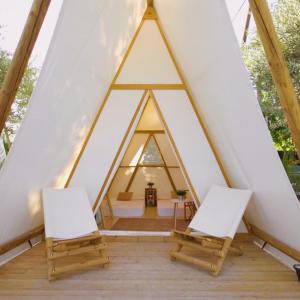 埃尔博斯克Kampaoh Grazalema的三角形帐篷内的2把椅子和1张桌子