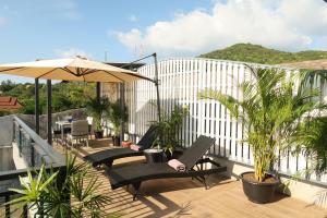 西塔努海之花简易别墅旅馆的阳台配有椅子、雨伞和植物