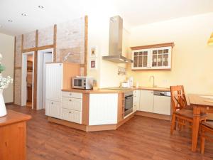 奥斯赛拜-塞林Villa "To Hus" in Sellin - WG 02 mit Kamin und Balkon的厨房铺有木地板,配有白色橱柜。