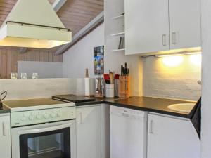 莱斯Holiday Home Gerarda - 4km from the sea in NE Jutland by Interhome的厨房配有白色橱柜和炉灶烤箱。