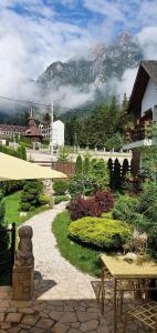 布什泰尼Pensiunea Turistica Villa Ermitage的一个带桌子和遮阳伞的花园以及山地