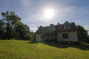 PilecChalupa Dejnowo的天空中阳光灿烂的草地上的房子