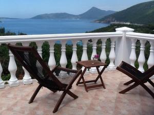 卢什蒂卡Villa Mirista的俯瞰水面的阳台配有两把椅子和一张桌子