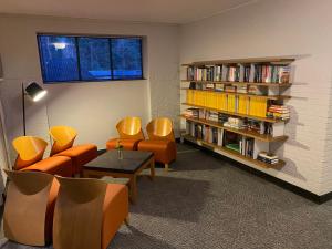 黑泽Hotel Kapellerput Heeze-Eindhoven的图书馆配有橙色椅子和书架