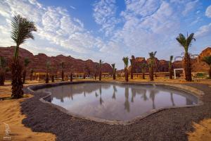 欧拉Sahary Al Ula Resort的沙漠中的一个小池塘,有棕榈树