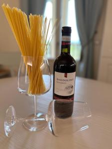 波佐伦戈Green Living Apartment的一瓶葡萄酒坐在意大利面的花瓶旁