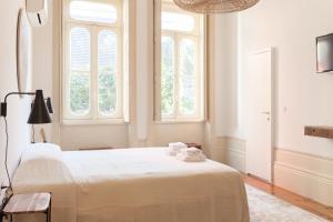 波尔图Alameda Suites - River Guest House的卧室配有一张白色大床和两个窗户