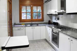 巴塞罗那Vacaciones en maresme casa para 7 personas的厨房配有白色橱柜和炉灶烤箱。