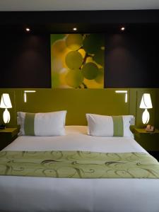 勒韦尔努瓦Golf Hotel Colvert - Room Service Disponible的卧室配有一张大床,墙上挂有绘画作品