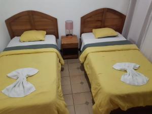 圣何塞20街精品酒店的配有两张黄色床单和毛巾的客房