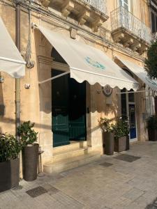 锡拉库扎Gran Bretagna Boutique Hotel Ortigia的一座带绿门和白色遮阳伞的建筑