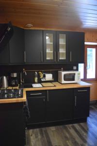 贝尔蒙特Les gîtes de la Serva的厨房配有黑色橱柜和台面上的微波炉