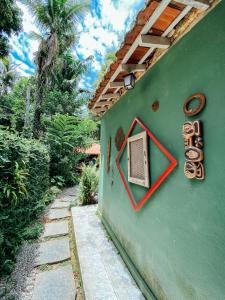 阿布拉奥Mambembe Hostel - Ilha Grande的房屋一侧有标志的绿色墙
