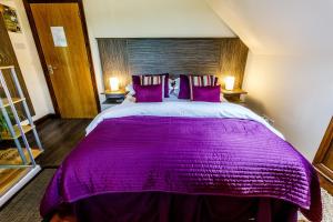 阿博因湖上小屋酒店的一间卧室配有一张大紫色床和两盏灯