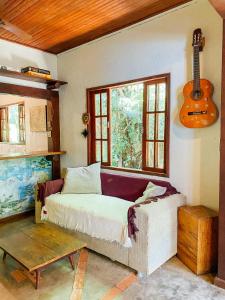 阿布拉奥Mambembe Hostel - Ilha Grande的卧室配有一张床,墙上配有吉他
