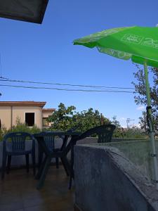 马莫亚达Affittacamere Cooperativa Olistica的庭院里配有桌椅和遮阳伞
