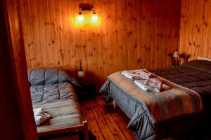 圣马丁德洛斯Cabaña El Maqui的一间带两张床铺的卧室,位于带木墙的房间内