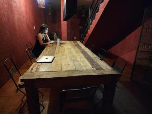 查克拉斯德科里亚Casa Lopez的坐在一张木桌旁的手提电脑的女人