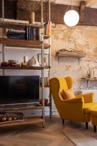 哈莱姆PASSAGE - historic boutique suite的客厅配有黄色椅子和电视