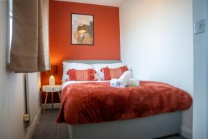米尔顿凯恩斯Comfortable 4 Bedroom Home in Milton Keynes by HP Accommodation with Free Parking, WiFi & Sky TV的一间卧室配有一张橙色墙壁的床