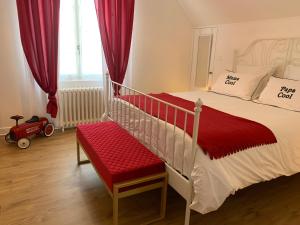 谢尔河畔努瓦耶CLOS DE LA BRIQUETERIE的一间卧室配有红色窗帘和红色长凳的床