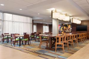 夏洛茨维尔Fairfield Inn & Suites by Marriott Charlottesville Downtown/University Area的用餐室配有桌椅和平面电视。