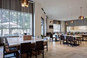 欧文Marriott Dallas Las Colinas的餐厅设有桌椅和大窗户。